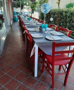BarbarascoSan Quirico Locanda ristorante pizzeria的一张长桌子,上面有红色椅子和蓝色的装饰