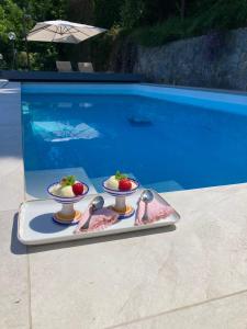 维耶特里Villa Lilia的两个碗草莓和汤匙放在泳池旁的托盘上