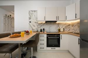 卡诺尼Kukos Apartment Corfu的厨房配有白色橱柜和木桌