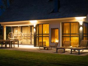 德科克斯多普Luxury villa with sauna near beach的房屋设有庭院,晚上配有桌椅
