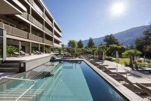 纳图尔诺Feldhof DolceVita Resort的酒店游泳池的背景是椅子和山脉