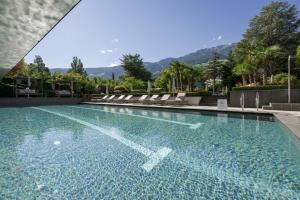 纳图尔诺Feldhof DolceVita Resort的一个带椅子的游泳池,背景是山脉