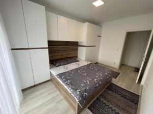 普里什蒂纳Plis Apartment II的一间小卧室,配有一张床和白色橱柜