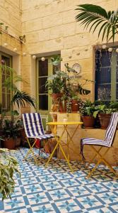 瓦莱塔Myrtle Suite - Valletta ground floor apartment的庭院设有两把椅子和一张桌子,种有植物