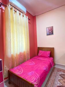 马兰MNOOR HOMESTAY的卧室配有粉红色的床和窗户。