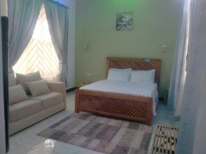 达累斯萨拉姆BabaJay Family Home的一间卧室配有一张床、一张沙发和一个窗口