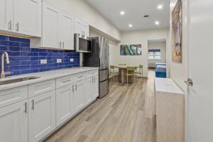 怀尔德伍德Seaport Suites的厨房配有白色橱柜和蓝色瓷砖墙。