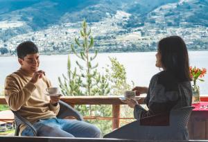 奥塔瓦洛Campo Lago Hospedaje的坐在桌子上喝咖啡的男人和女人
