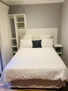 KroondalTen Flags Theme Park的卧室配有白色大床和白色枕头