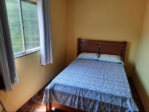 特雷索波利斯Teresópolis Hostel的一间卧室配有一张带蓝色棉被的床和窗户。