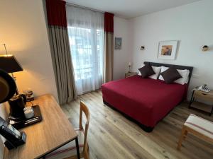 康博莱班Hôtel Ursula的酒店客房配有红色的床和一张桌子