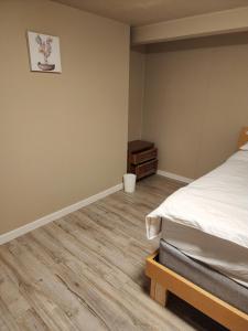 伯纳比Economical Homestay的一间卧室配有一张床,铺有木地板