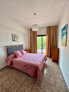 圣埃乌拉利亚Hostal y Apartamentos Santa Eulalia的卧室设有粉红色的床和大窗户