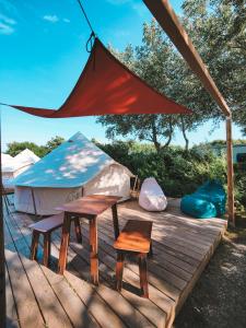 WesterwallDOMO CAMP Sylt - Glamping Camp的木制甲板上的圆顶帐篷,配有2张桌子和椅子