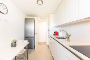 马德里Piso climatizado y parking的厨房配有白色橱柜和不锈钢冰箱