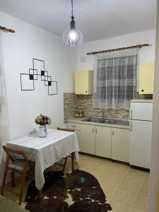 斯库台Dibra Home near City Center of Shkodra的厨房配有白色的桌子、水槽和桌椅