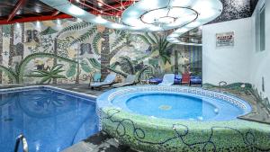 托卢卡Suites Inn la Muralla Hotel & Spa的一间带按摩浴缸和壁画的浴室