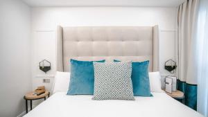 马德里里贾纳酒店的一间卧室配有白色床和蓝色枕头