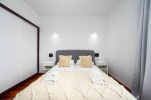 格但斯克White Sea - Neptun Park by OneApartments的一间卧室配有一张带2个床头柜的大床