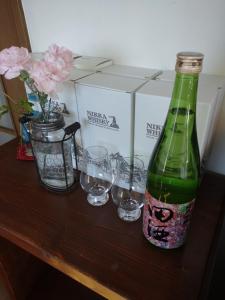 网走市Abashirikai no Taiyo - Vacation STAY 14415的木桌上放有绿瓶和玻璃杯