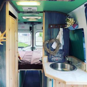 SkewenAnnie The Ambulance (Drive away campervan)的一间带水槽的浴室和一张位于走廊的床铺