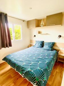 La BétaudièreÉvasion océanique : Mobil-home dans un camping 4* à 50m de l'océan的一间卧室配有一张带蓝色棉被的床