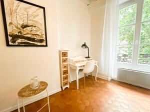 索恩河畔沙隆"Douceur de vignes", cosy, coeur de ville, Classé 3 étoiles - BY PRIMO C0NCIERGERIE的客房设有书桌和带台灯的桌子。
