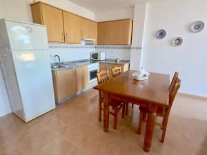 拉科萨加拿大公寓 的厨房配有木桌和白色冰箱。
