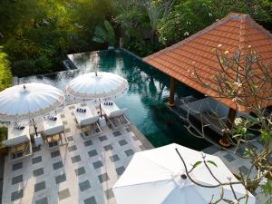 坎古Adepa Resort的水边的游泳池配有白色遮阳伞和椅子