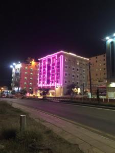 巴勒如拉斯فندق وشقق ليالي الاحلام للشقق المخدومه的街上用粉红色灯点亮的建筑物