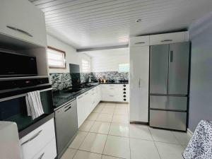 皮特尔角城Charmante Villa, kaz’ AA.Liyah的一间大厨房,配有白色橱柜和不锈钢冰箱
