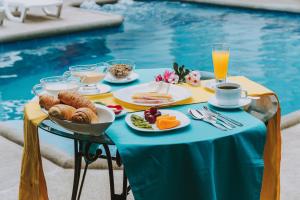 比亚米尔港Galápagos Isabela Hotel Loja的池畔餐桌上摆着早餐食品