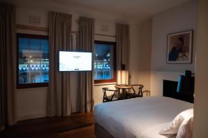 弗里曼特Warders Hotel Fremantle Markets的一间卧室配有一张床和一台平面电视