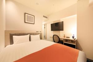 鹿儿岛QuintessaHotel KagoshimaTenmonkan Relax&Sleep的一间卧室配有一张床、一张书桌和一台电视。