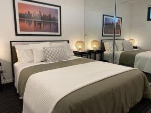 墨尔本Modern Quiet 1 & 2 Bed Apt Opposite Albert Park的一间卧室配有两张床和两盏灯。