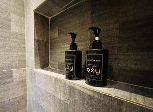 巴淡岛中心oxy suites G-03 at Shop House Meisterstadt Pollux Habibie的浴室内架上两瓶黑洗发水
