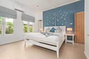 拉迈2BR Villa Baan Orchid, seconds to beach的卧室配有白色床和蓝色墙壁