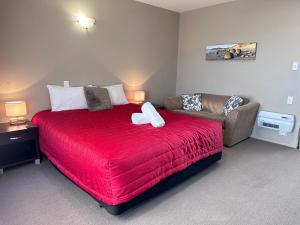 奥玛鲁奥玛鲁遗产庭院汽车旅馆的一间卧室配有红色的床和一张沙发