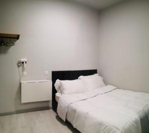 哥打京那巴鲁LILO Staycation JQ的一间卧室配有一张白色的床和黑色床头板