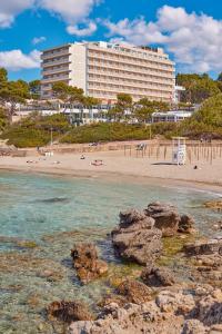帕格拉Universal Hotel Lido Park & Spa的海滩上一座大建筑,在水中岩石