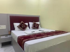 孟买Hotel Sai Plaza, Chembur Mumbai的一间卧室配有一张带红色和白色枕头的大床