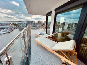 不来梅港COAST HOUSE Seaside Loft的阳台配有白色椅子,享有海港景色