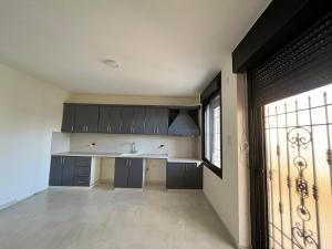 Al KhalīlGerman-Palestinian Appartement的厨房配有黑色橱柜、水槽和窗户。