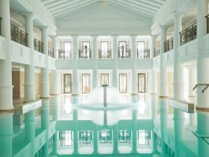 卢特拉基利尼斯Grecotel Ilia Palms & Aqua Park的一座位于大楼中间的带桌子的室内游泳池
