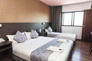 马普托Hotel Kapital的酒店客房设有两张床和窗户。