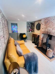 KentLittle Pilgrims Retreat in St Dunstans, Canterbury的客厅设有黄色沙发和砖砌壁炉