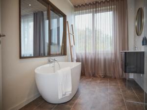 格罗斯滕本尼克卡尔德酒店的一间带大型白色浴缸和镜子的浴室