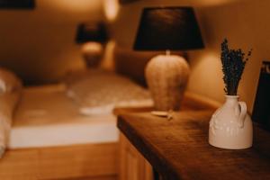 PolzelaLavender Hill, Eko Resort & Wellness的一间卧室配有一张床和一张桌子,配有一盏灯和花瓶