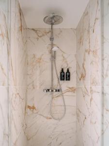 巴黎Solly Hôtel Paris的带淋浴的浴室(以白色大理石装饰)