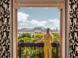巴黎Solly Hôtel Paris的穿着黄色衣服的女人,从窗户望着凡尔赛宫